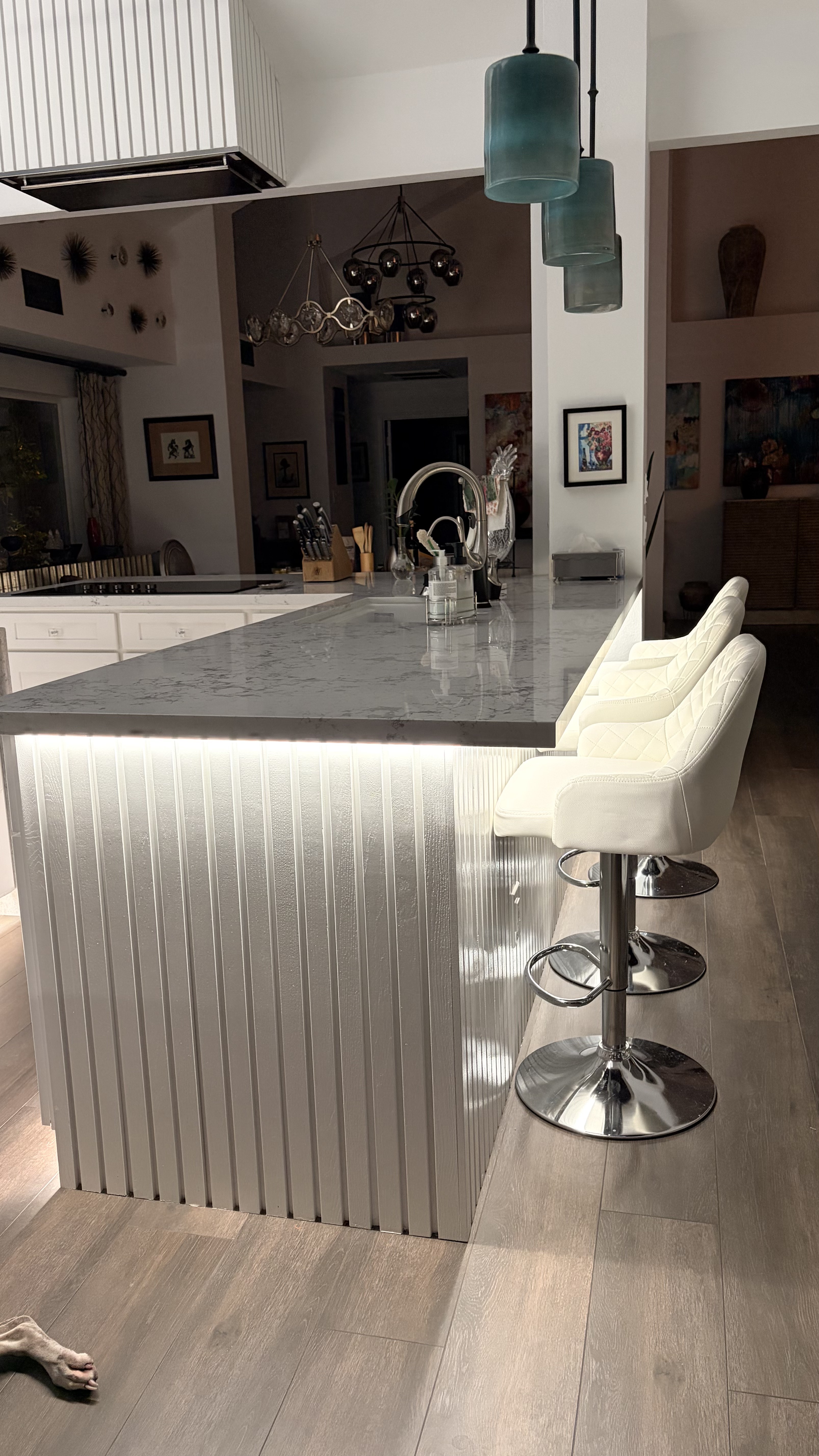 Modern kitchen island featuring integrated warm white LED backlighting behind decorative fluted panels.
