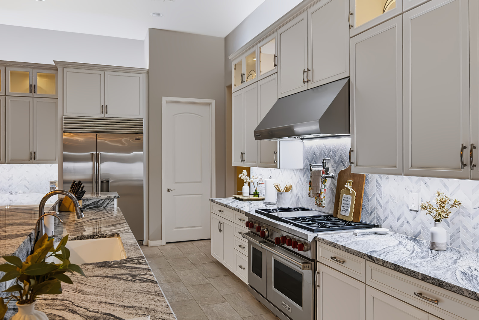 White kitchen with bright under cabinet lighting illuminating a herringbone backsplash, countertops and professional style range.
